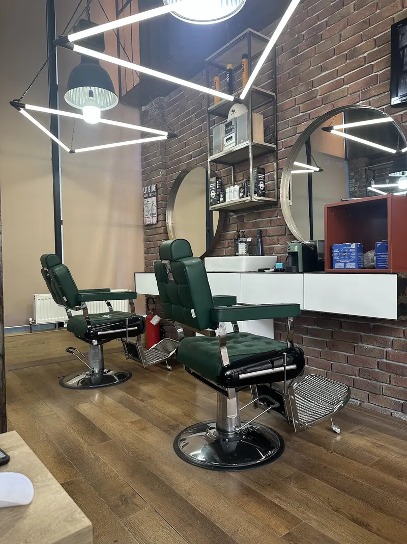 Two green barber chairs in front of the brick wall